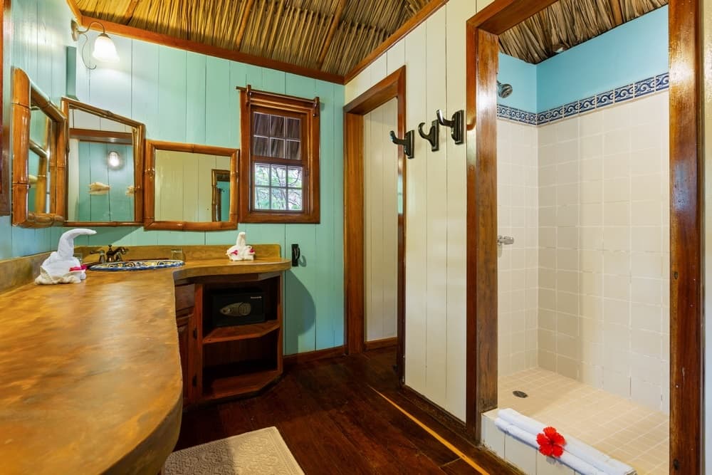 A bathroom with a rustic yet elegant design, featuring a large wooden vanity with a double mirror, a spacious walk-in shower, and a private toilet area.