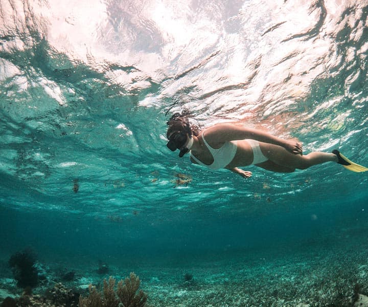 A person snorkeling underwater in a clear ocean.
