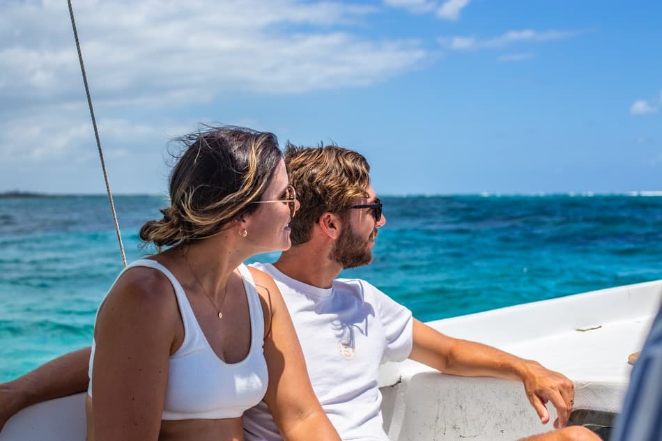A couple sits on a boat, gazing out at the ocean.