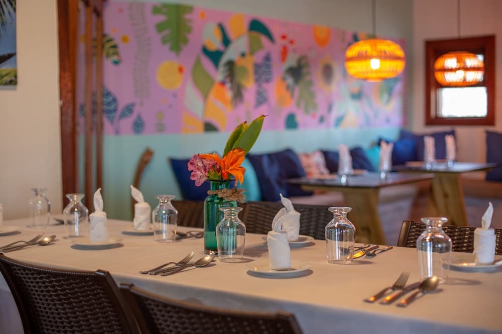 A dining table set with glassware and a floral centerpiece in a colorful restaurant interior.