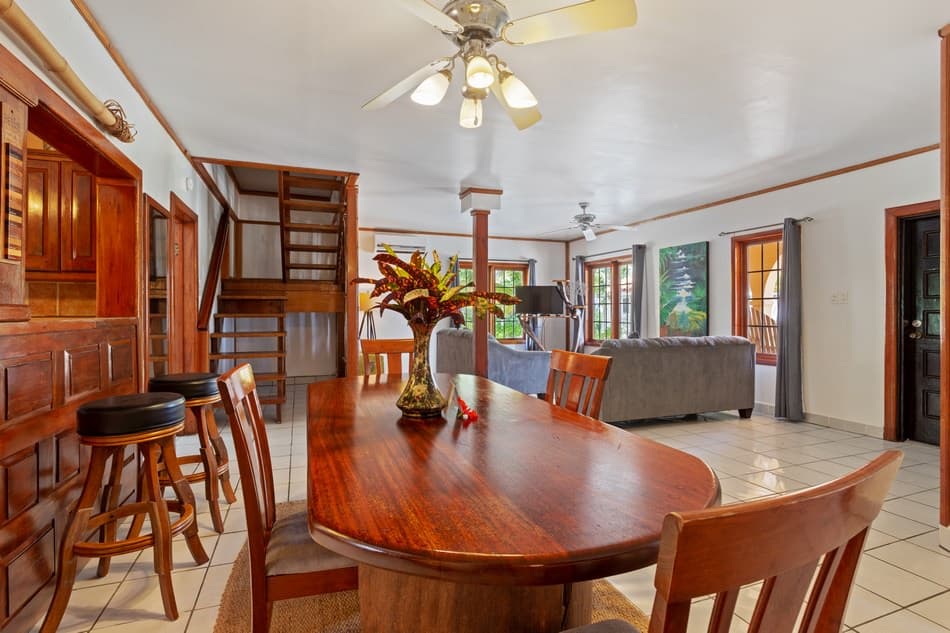 A spacious dining area with wooden furniture and views into a bright living room.
