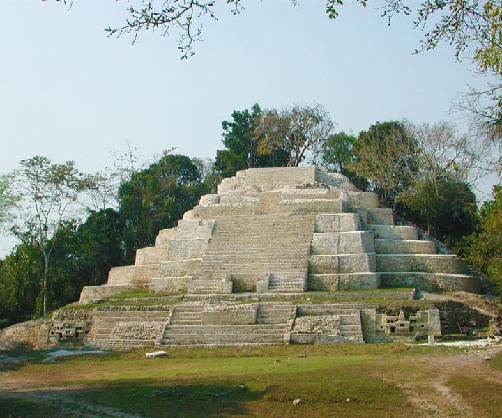 A stepped ancient pyramid surrounded by lush greenery.