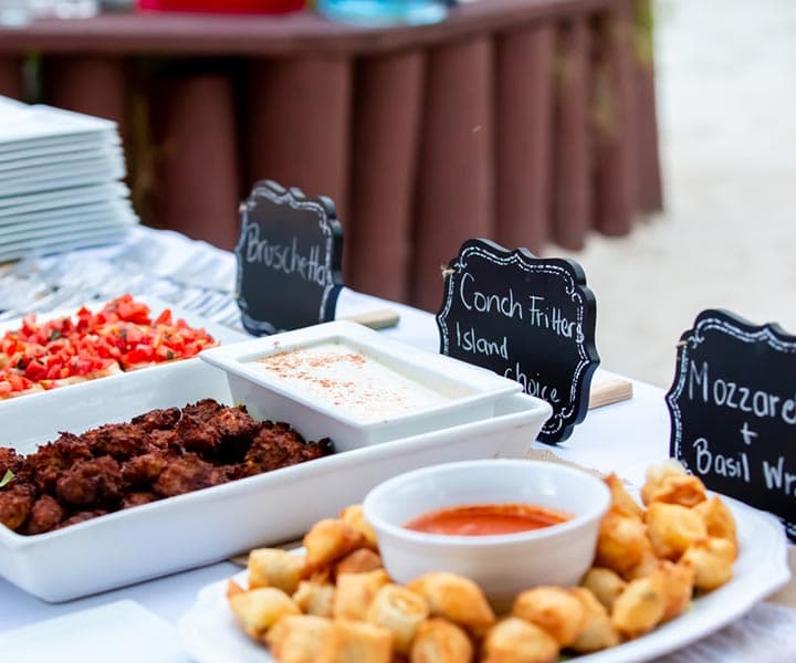 A selection of appetizers including bruschetta, conch fritters, mozzarella bites, and dipping sauces arranged on a table.
