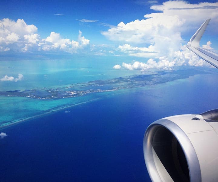 Aerial view of turquoise waters and land from an airplane window.