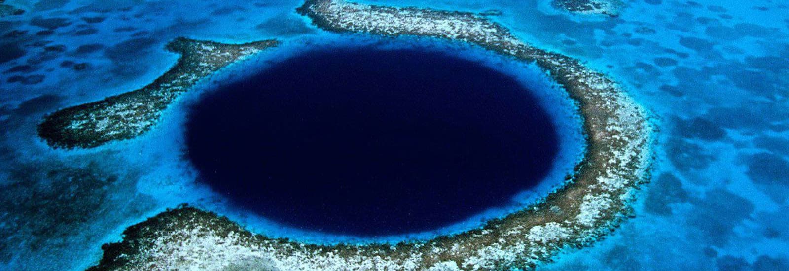 Aerial view of the Great Blue Hole in Belize, a large, deep blue circular sinkhole surrounded by vibrant turquoise water and coral reefs. Majestic and serene.