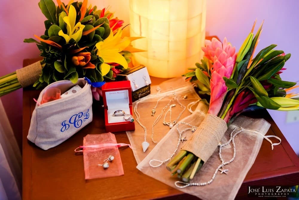 A collection of wedding accessories including bouquets, jewelry, and a cosmetic pouch arranged on a wooden surface.